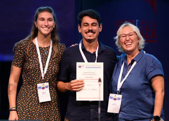 Dr. Camilla Roveta (l.) und Dr. Eva Turicchia (r.), ECRS2024 Student and Early Career Advisory Board, übergeben die Urkunde an Gabriel Cardoso.