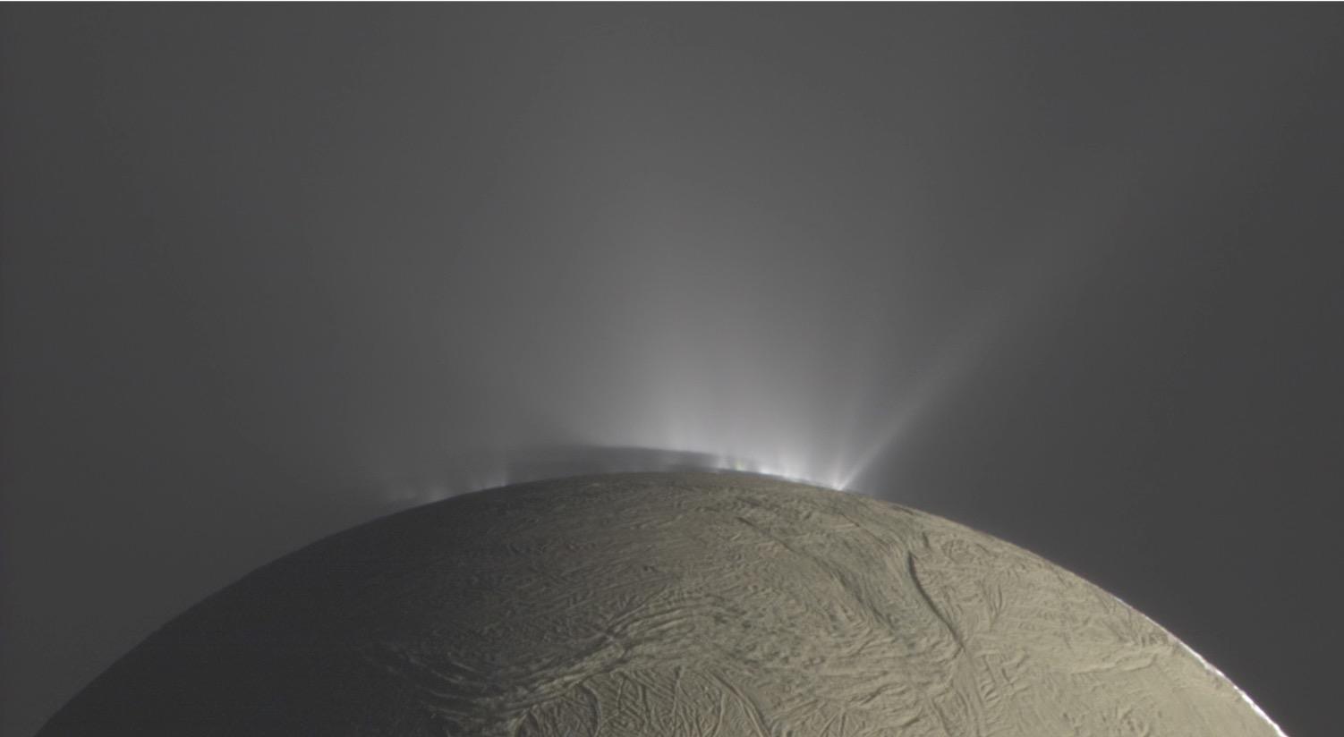 Aus Rissen in der Eiskruste des Enceladus schießen cryo-vulkanische Eisfontänen ins All hinaus. Die Eispartikel entstehen aus dem globalen Ozean, der sich unter der einige Kilometer mächtigen Eiskruste befindet.